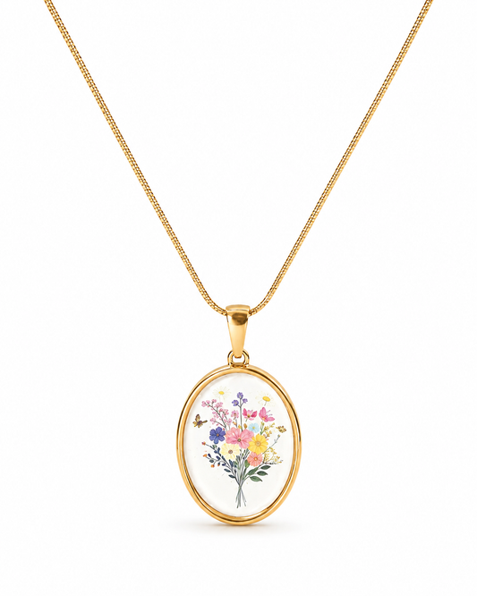 A gold chain necklace with an oval pendant featuring a colorful watercolor-style bouquet of flowers, shown on a clean white background.