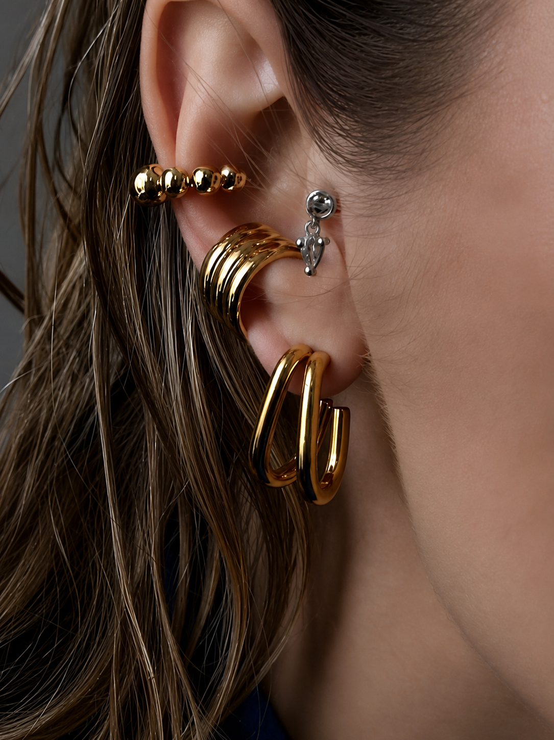 Model wearing the Mindfull Ear Cuff in 18K gold-plated stainless steel, styled with layered gold earrings for a modern stacked ear look.