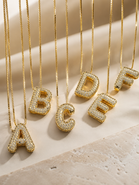 Gold initial pendant necklace with a cubic zirconia letter charm on a fine chain, crafted from steel with 18K gold plating.