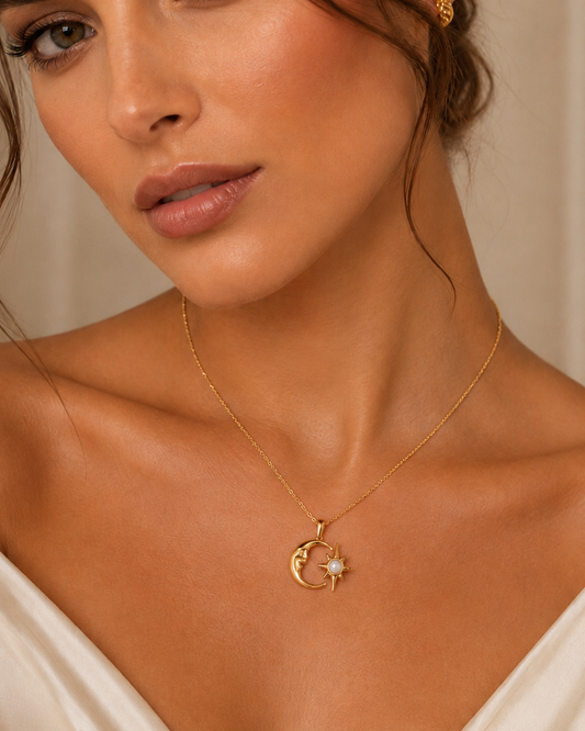 A close-up of a woman wearing a delicate gold necklace with a crescent moon and star pendant featuring a small white pearl accent.